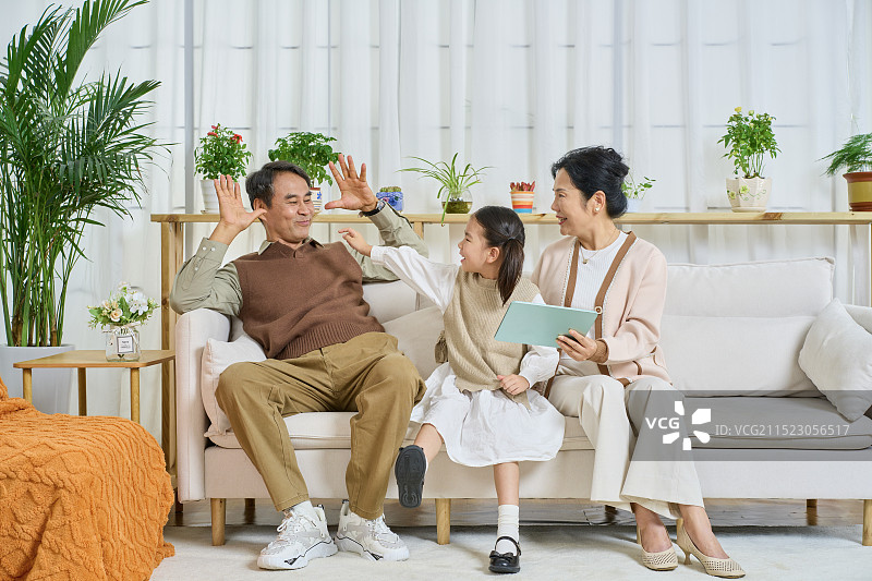 祖孙三人坐在沙发上一起看平板电脑图片素材