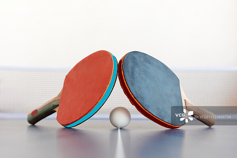 蓝色乒乓球桌上的红黑乒乓球拍和白色乒乓球网架图片素材