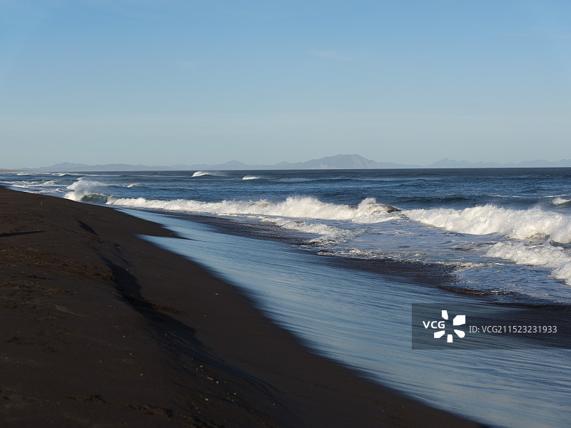 堪察加黑沙滩晴空下的蓝色海浪图片素材