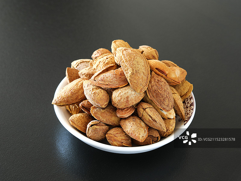 黑色桌面上的一碟子春节年货坚果巴旦木图片素材