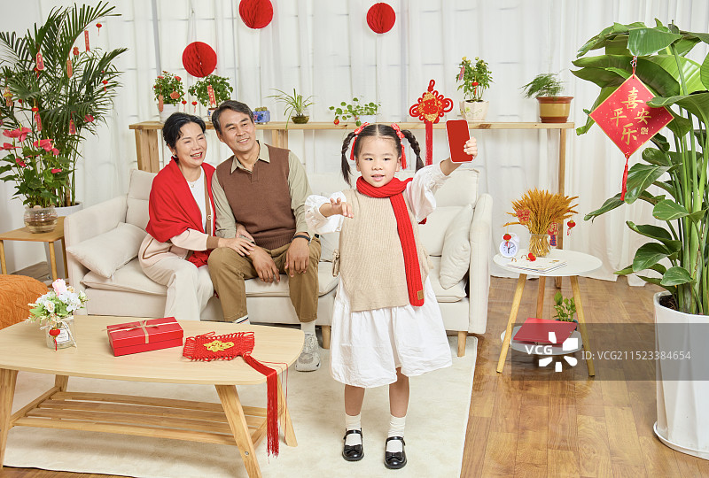 春节里站在镜头前的手拿手机的小女孩图片素材