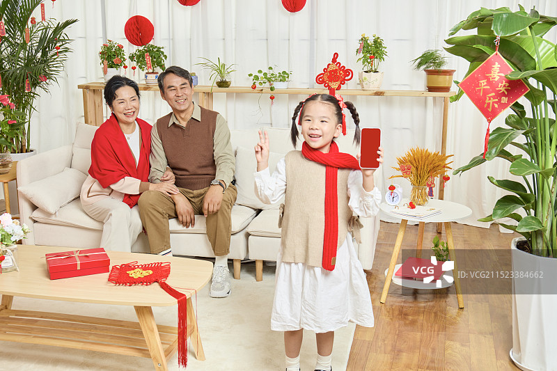 春节里站在镜头前的手拿手机的小女孩图片素材
