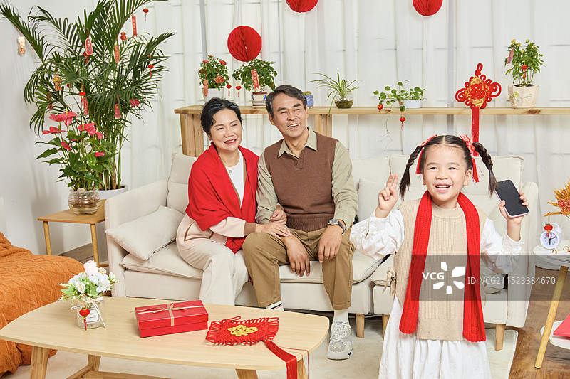 春节里站在镜头前的手拿手机的小女孩图片素材