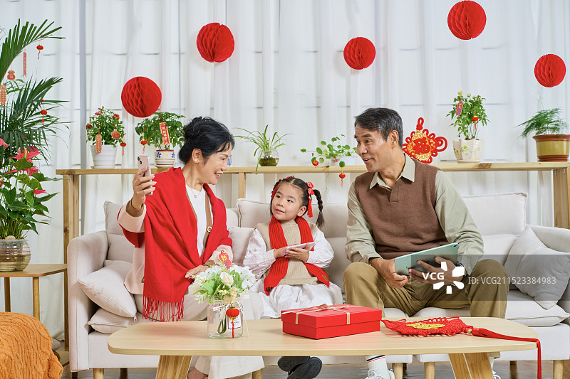 坐在沙上使用手机拍合影的祖孙三人图片素材