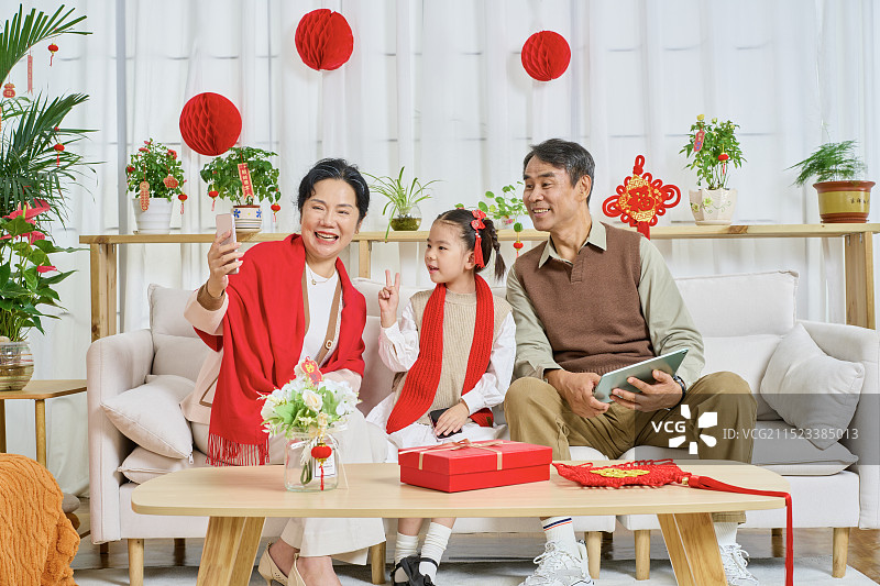 坐在沙上使用手机拍合影的祖孙三人图片素材