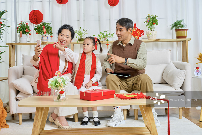 坐在沙上使用手机拍合影的祖孙三人图片素材