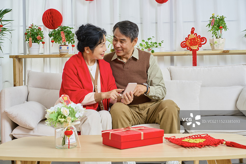 肩并肩坐在一起分享手机的老年夫妻图片素材