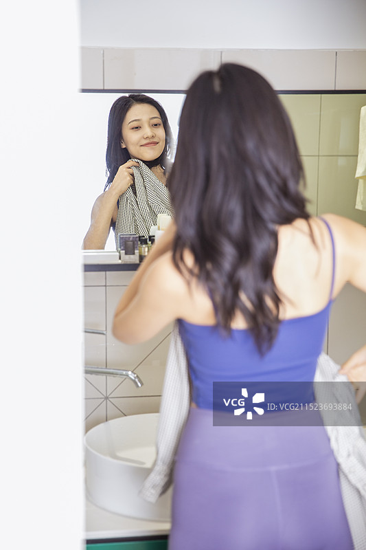 青年女子在卫生间挑选衣服准备出门图片素材