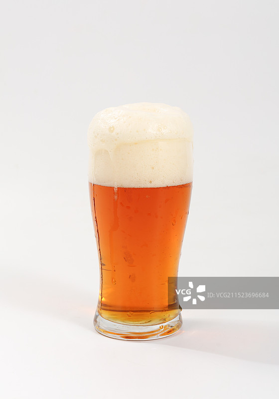 白色背景上，一杯啤酒泡沫已溢出图片素材