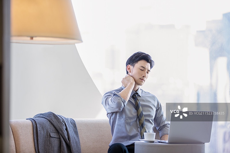 疲惫的男商人在酒店房间工作后按摩脖子图片素材