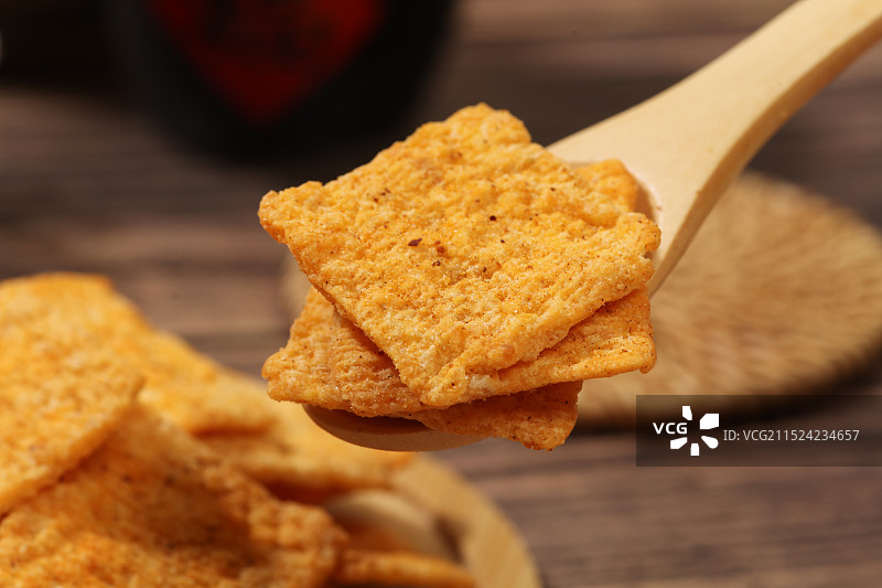木纹背景上，木勺里的香辣味锅巴图片素材