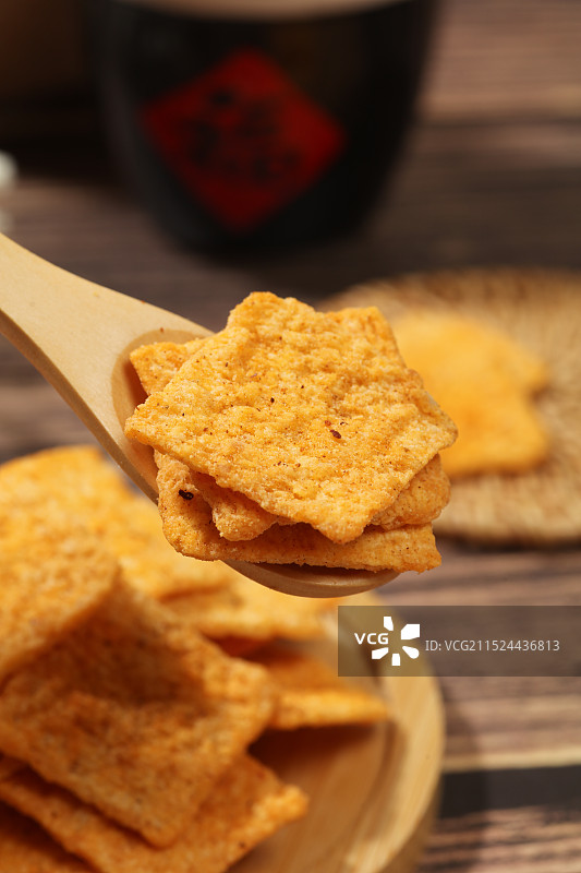 木纹背景上，木勺里的香辣味锅巴图片素材