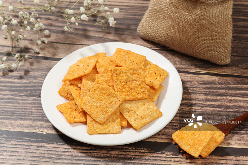 木纹背景上，香辣味锅巴摆放在盘子里图片素材