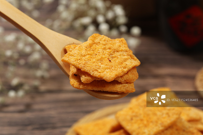木纹背景上，木勺里的香辣味锅巴图片素材