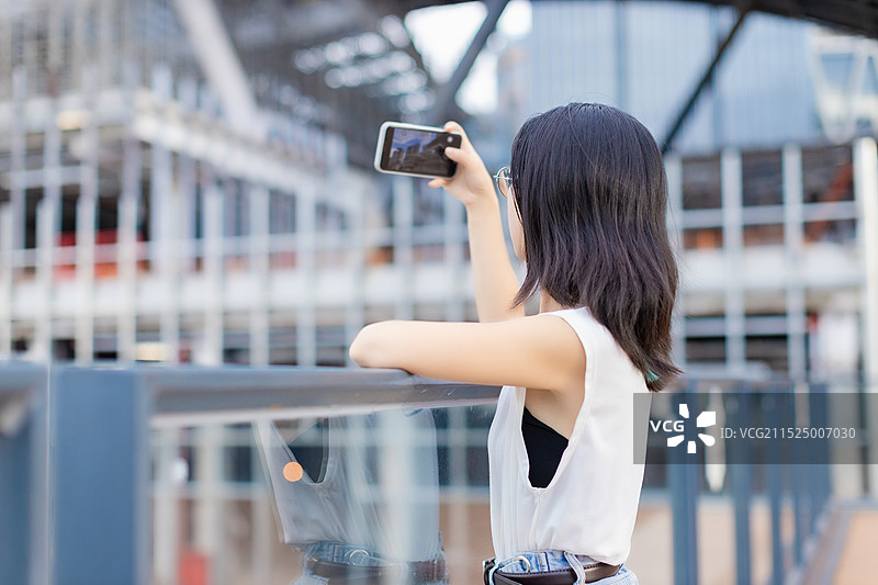 女生拿着手机在城市建筑广场图片素材