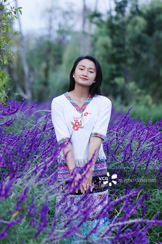 站在紫色花草旁的女人肖像图片素材