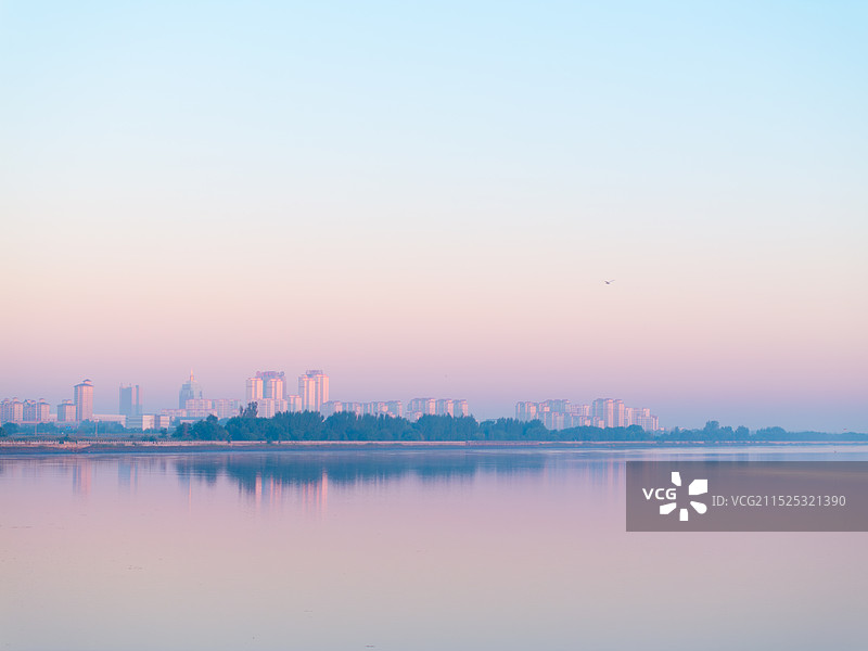 日出时城市倒映在平静的湖面上图片素材