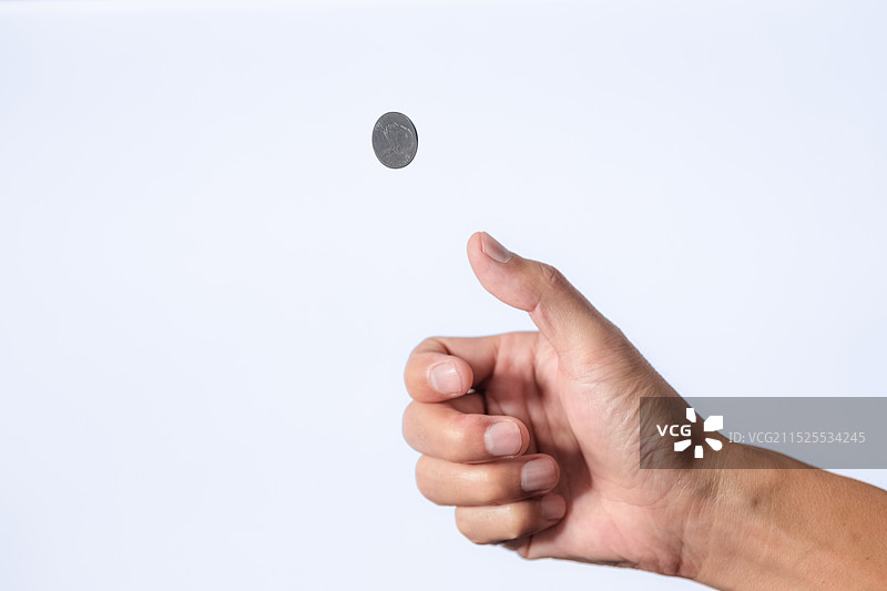 男性的手抛起硬币，在白色背景前图片素材