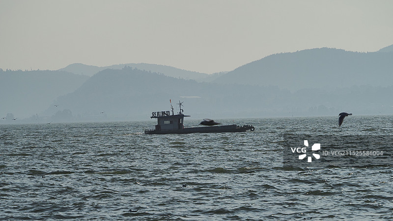 滇池里的船在天空下与群山的轮廓图片素材