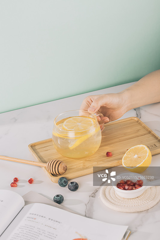 制作蜂蜜柠檬水，一只手握着杯子静物美食图片素材