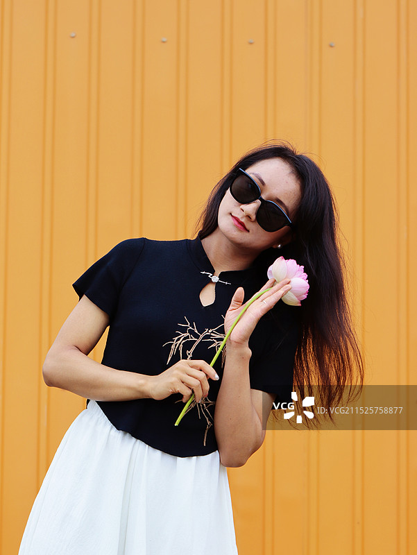 站在黄色墙上的年轻女子图片素材