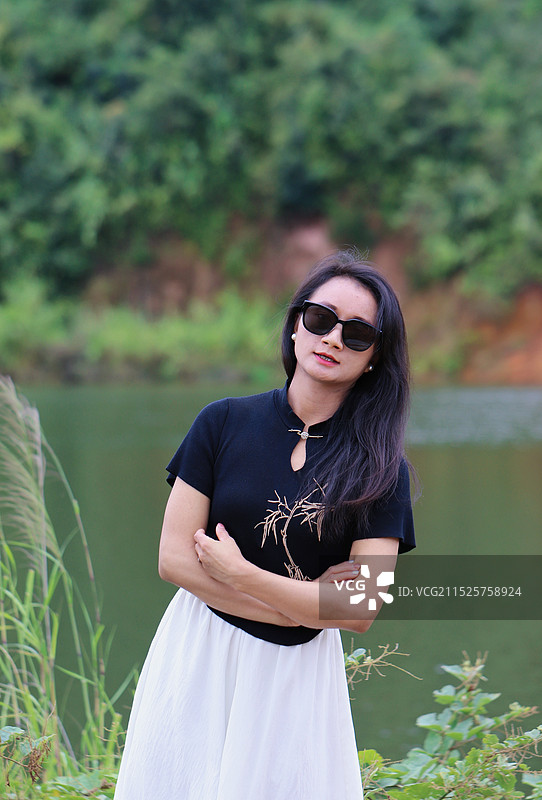 戴墨镜的年轻女子站在湖边的肖像图片素材