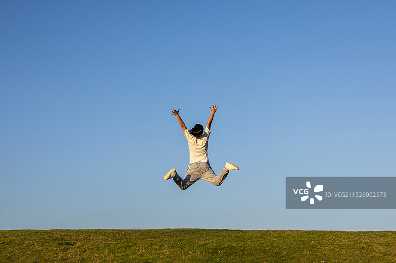 蓝天草地一名中国女人跳起来图片素材