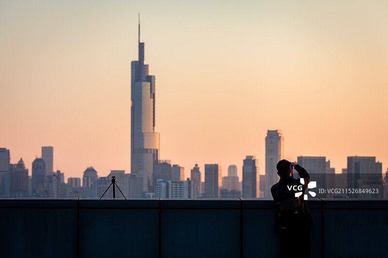 日落时站在城市建筑物旁的人的剪影图片素材