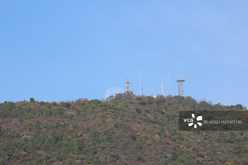 白天月亮隐没在山顶气象站长焦特写图片素材