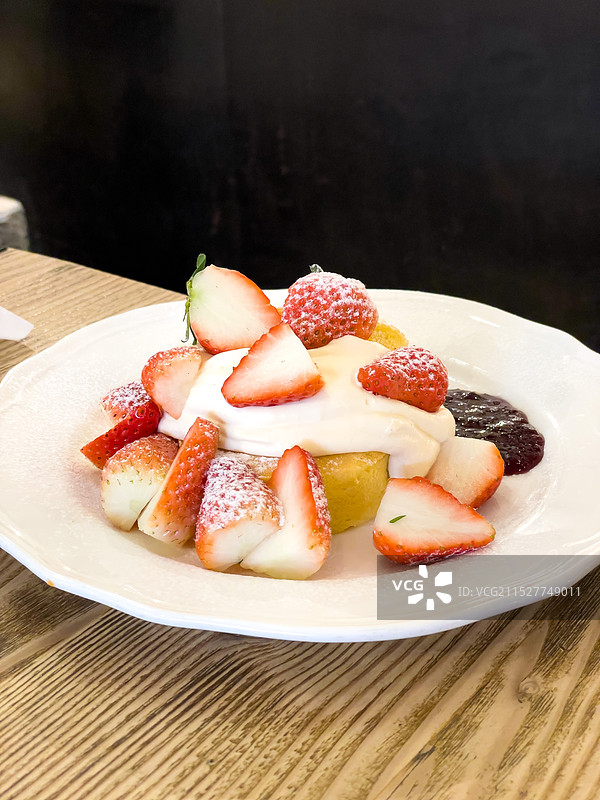 餐桌上白色瓷盘中的草莓奶油舒芙蕾甜点图片素材