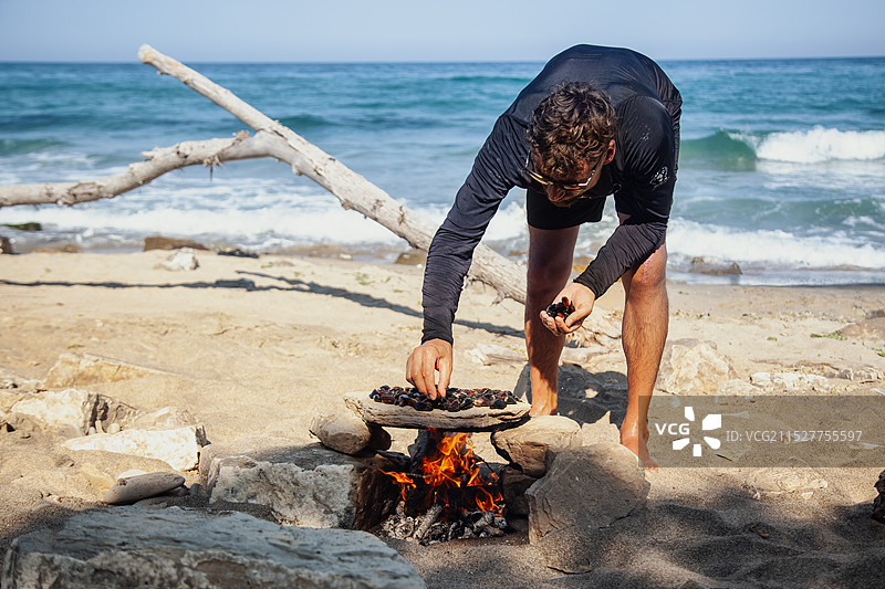 海滩上，贝类在石头上火烤，背景是大海。图片素材