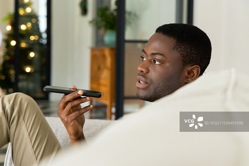 非裔美国男性在家中使用智能手机语音命令庆祝圣诞节图片素材