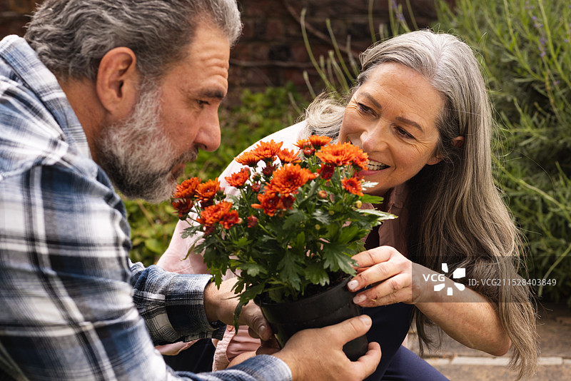 成熟夫妇在户外一起享受园艺，欣赏后院中绚丽的花朵。图片素材