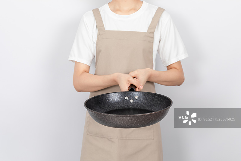 白色背景中一个年轻女人手拿麦饭石平底锅图片素材