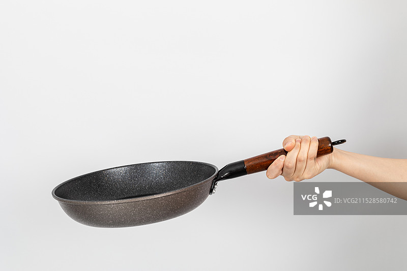 一只手拿着空的麦饭石平底锅颠锅动作图片素材