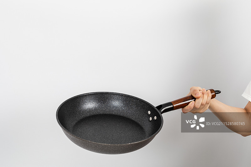 一只手拿着空的麦饭石平底锅颠锅动作图片素材