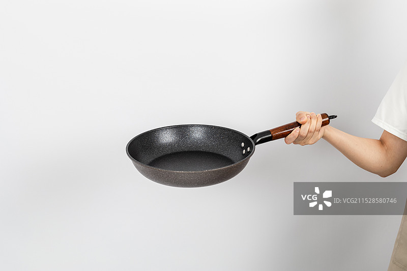 一只手拿着空的麦饭石平底锅颠锅动作图片素材