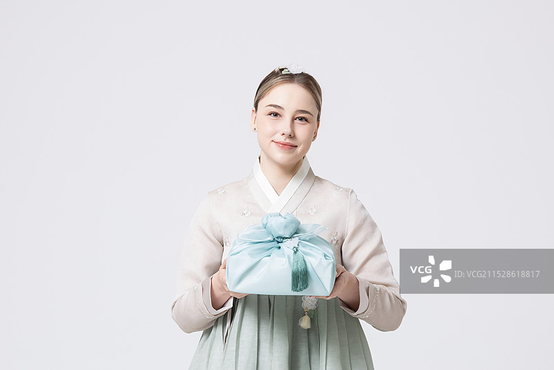 穿着韩服的西方女性手持用韩国风格包装的礼物图片素材