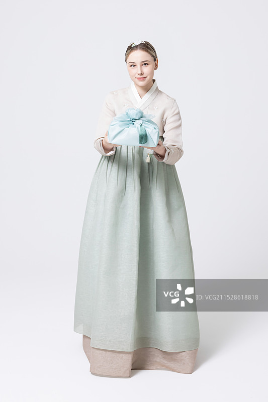 穿着韩服的西方女性手持用韩国风格包装的礼物图片素材