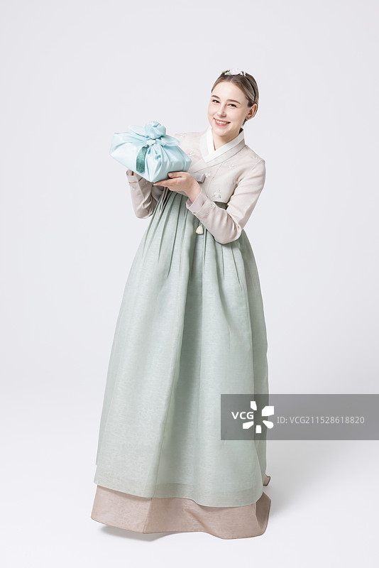 穿着韩服的西方女性手持用韩国风格包装的礼物图片素材