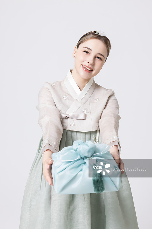 穿着韩服的西方女性手持用韩国风格包装的礼物图片素材