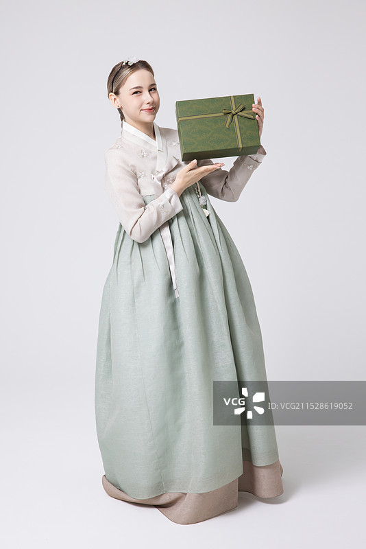 一位外国女性穿着传统的韩国韩服，手里拿着节日礼物图片素材