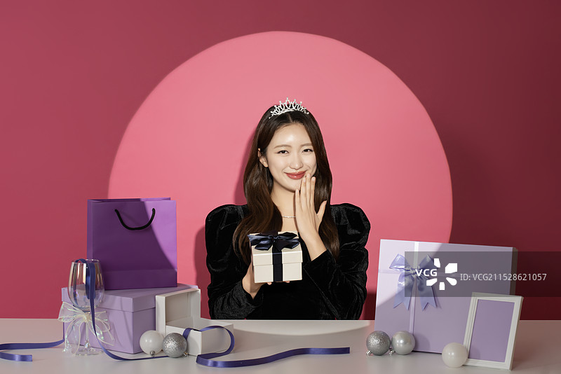 一位20多岁的女性主角在各种礼物面前受到关注和瞩目。图片素材