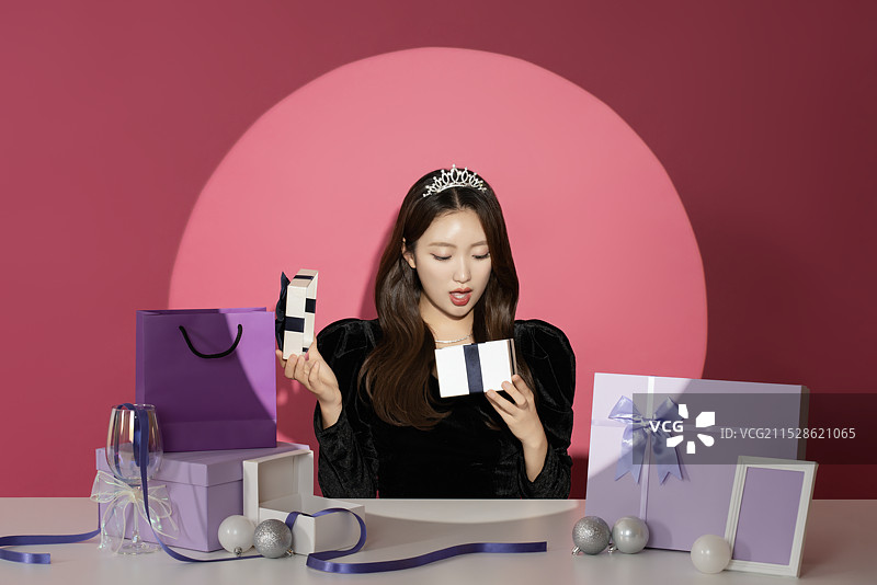一位20多岁的女性主角在各种礼物面前受到关注和瞩目。图片素材