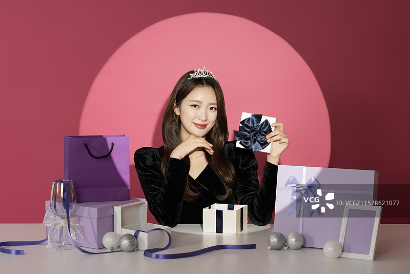 一位20多岁的女性主角在各种礼物面前受到关注和瞩目。图片素材