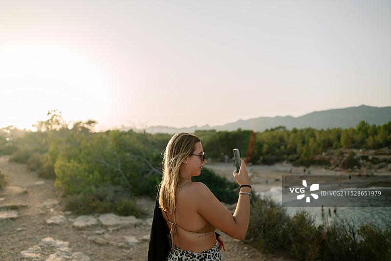 女人在拍摄日落的照片图片素材