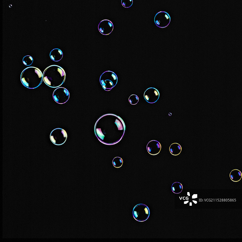 七种闪亮颜色的肥皂泡在黑色背景中漂浮图片素材