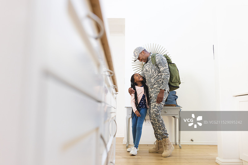 快乐的非裔美国男性士兵在家中拥抱女儿，留白空间图片素材