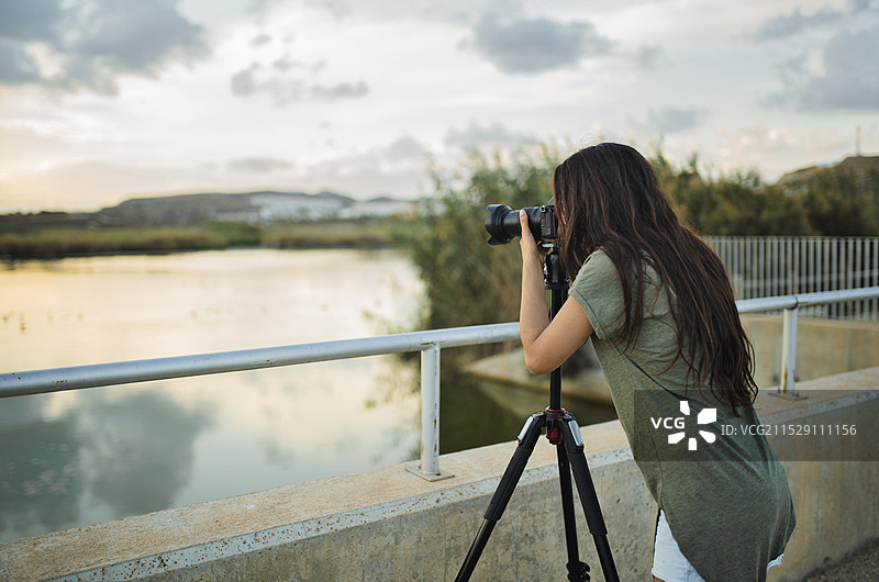 一位女性摄影师在盐滩上使用三脚架拍照的背影图片素材