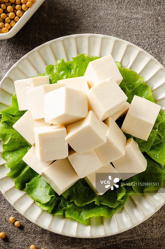 切成小块的新鲜豆腐放在铺满蔬菜的盘子上图片素材